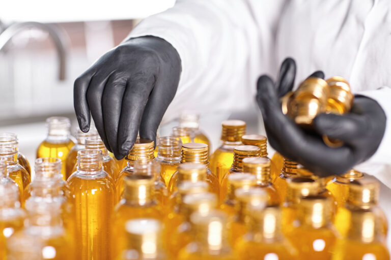 factory-worker-white-gown-rubber-gloves-screwing-bottle-caps